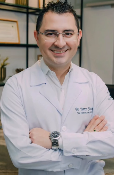 Dr. Juarez Silvestre sorrindo, de jaleco branco, em seu consultório
